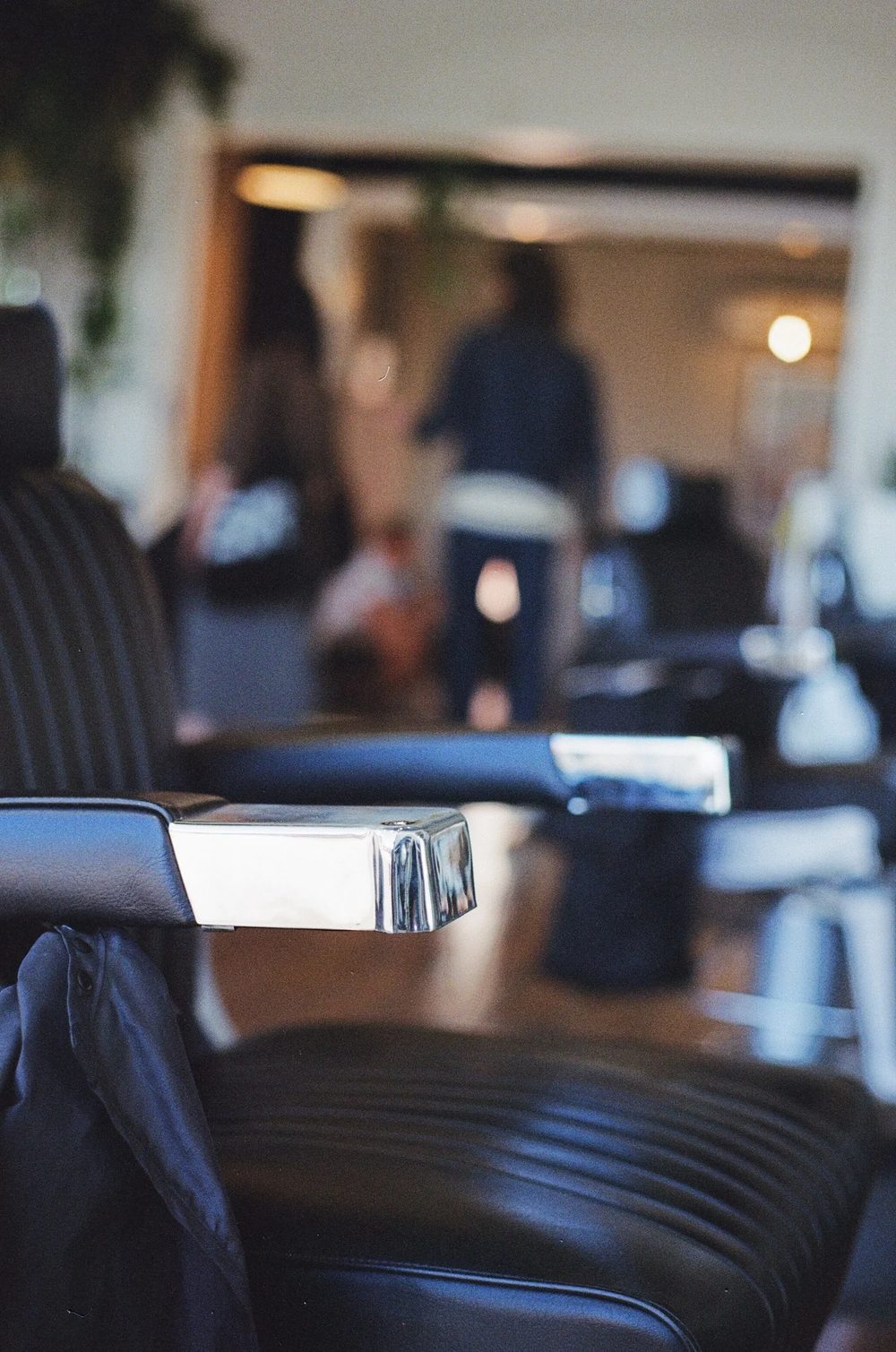 Leather barber chair with a chrome armrest inside Paragon Studio